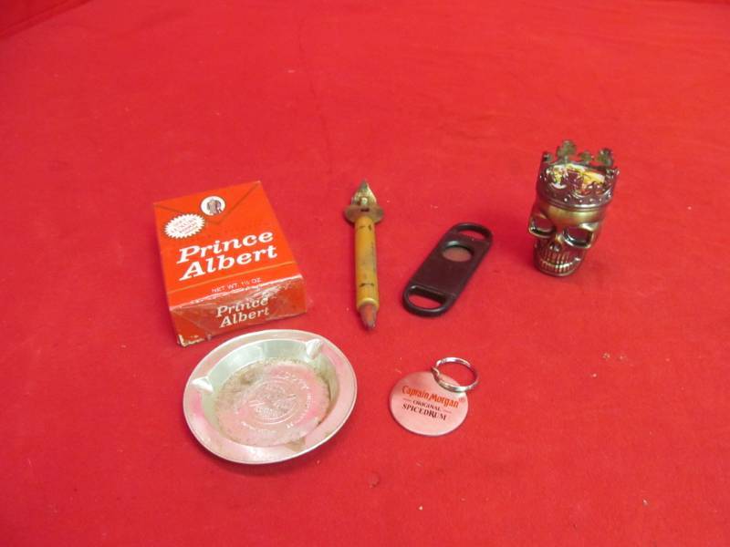 lot 12 image: Prince Albert soft luxury pouch, ash tray, cigar clipper, skull with crown