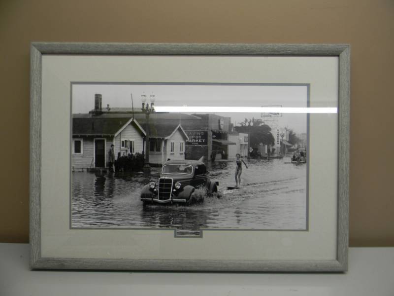 lot 22 image: SURFIN USA BLACK & WHITE FRAMED - GIRL SURFIN THE STREETS OF LA LATE 1930s - SEE PICTURES