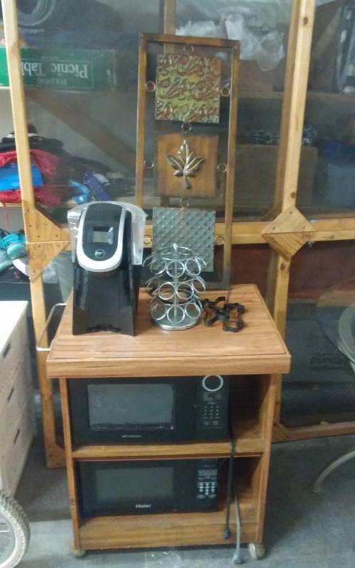 lot 9 image: Micro Wave Stand With 2 Micro Wave Ovens, Keurig Coffee Maker, Cup Caddy, & Ornate Metal Wall Decor.