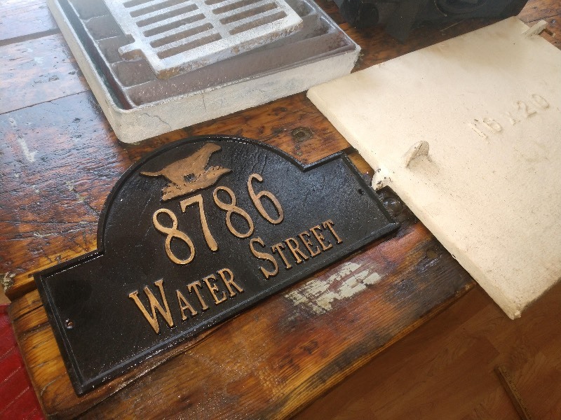 lot 14 image: Floor Drain Grates, 8786 Water Street Plaque, 1920s Coal Boiler Shute Door, Vintage Trunks