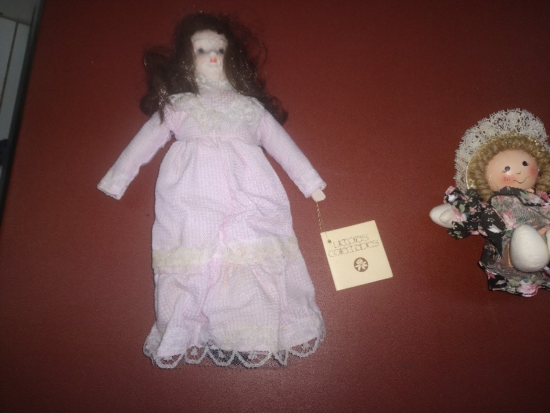 lot 93 image: Victorias Collectible Doll- Dark Brown Hair Pink Dress - Curly Hair Blonde Doll with Black Floral Dress - Santa Doll - Scarecrow Lady with Red Pants and Straw Hat Doll - Girl and Boy Doll