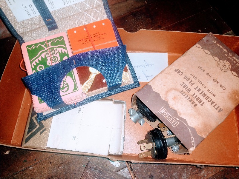 lot 113 image: White Wire Shelving - White Towel Bar - Bakelite Three Wire Attachment Plug Cap - Vintage Blue Portfolio Card Holder - Vintage Knit Rope Clothesline on Wood Spindle - Black Piece of Steel - Blue-Gray Vice Tool - Marble-Like Lamp Base - 1315 Wooden Plaque