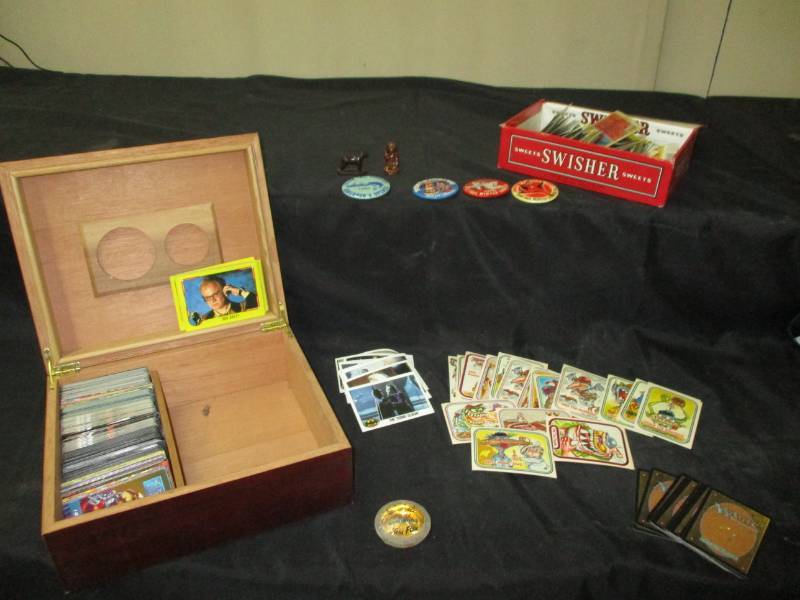 lot 92 image: Batmans, Dick Tracy, WWF, Xmen and varioty of cards and old pins in a humador and cigar boxes