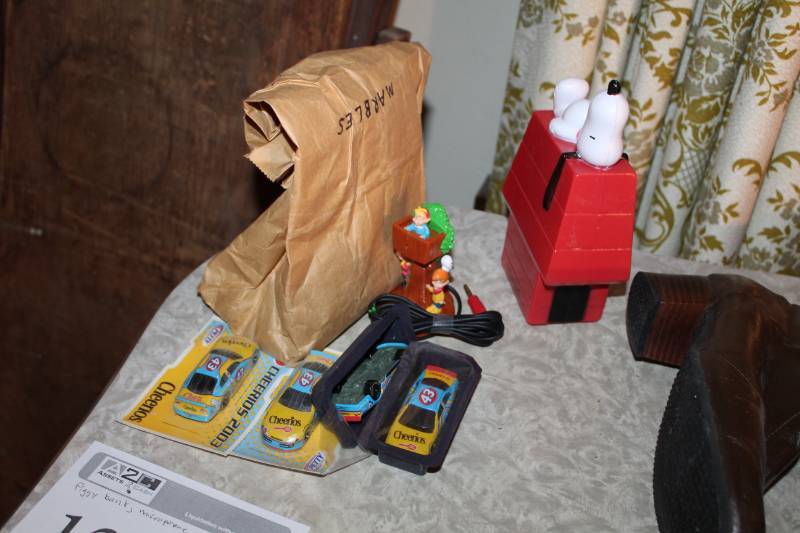 lot 128 image: Snoopy Piggy Bank, Microphone, Cheerios 143 Scale Collectible Cars, Bag of Marbles