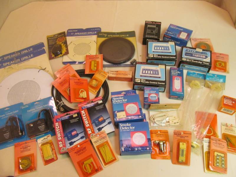 lot 208 image: NIP- large group home security and TV items- controled timers, motion sensors, switches, smoke detectors, speaker grilles