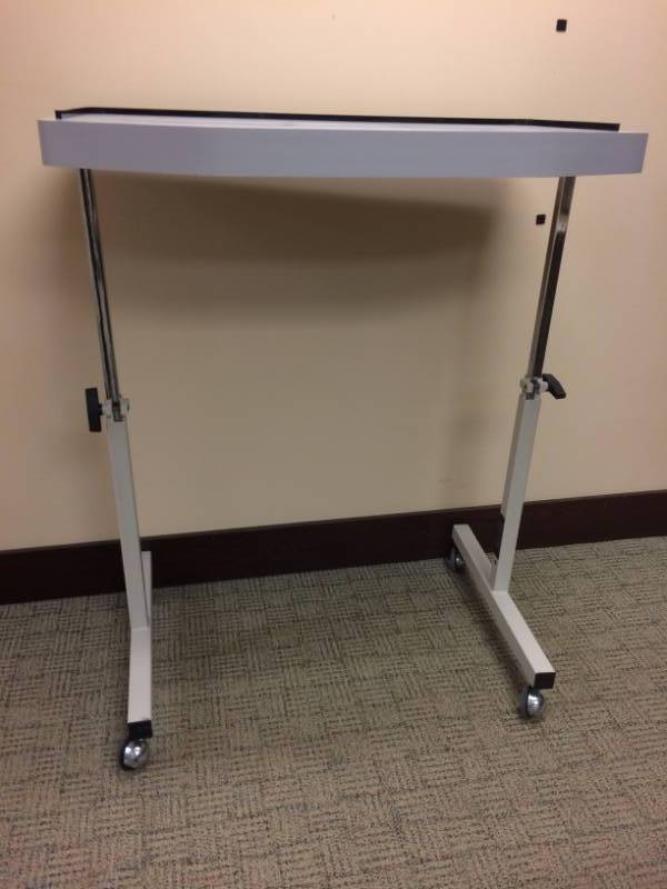 lot 71 image: Wow Mobile Height Adjustable Table With Extra Wide Tabletop That Includes A 34 Band Around It To Prevent Items From Rolling Off - Excellent Condition