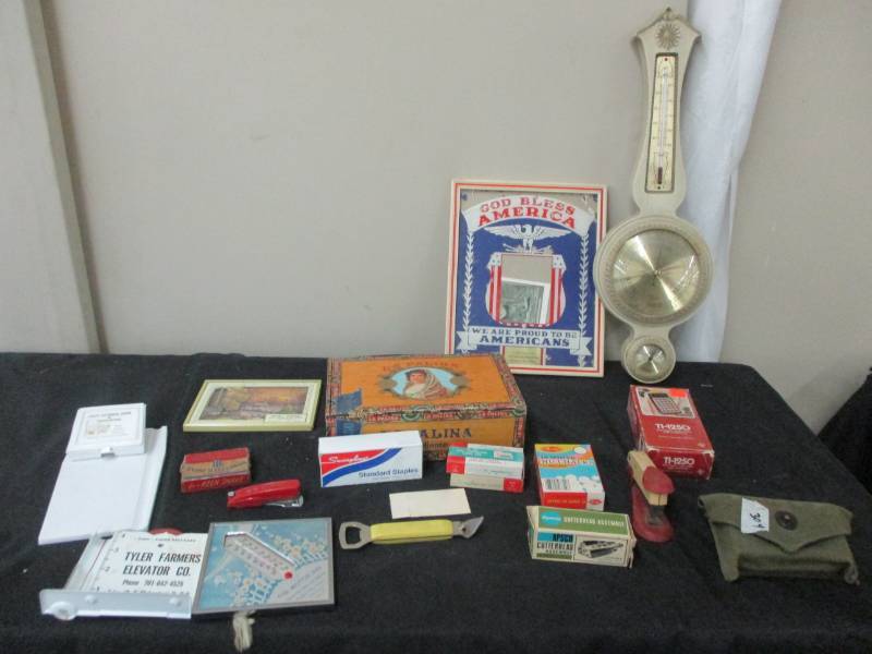 lot 108 image: Berometer, Military Bandages from 1944, Advertising pieces from Tyler Farmeras Elevator, First National Bank of Breckenridge Mn, The Motor Inn in Battle Lake, Vertins inn Wahpeton , stapler, and Staples