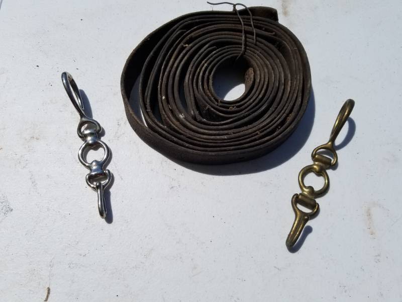 lot 153 image: Two horse or saddle hooks and a roll of leather