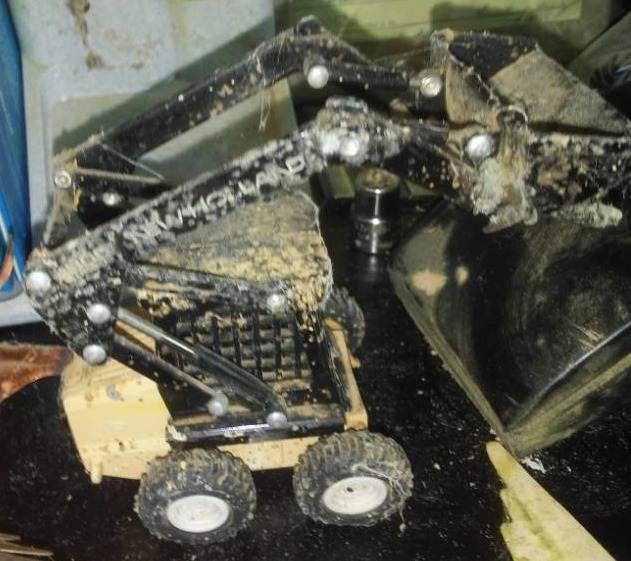 lot 260 image: Miscellaneous garbage can metal Decor, New Holland toy skid steer, ankle weights and more.