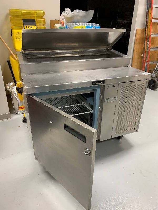 lot 15 image: Delfield Single Door Stainless Steel Raised Rail Pizza Prep Table on Casters - Model # NA - 115 Volts - 10 Amps - 48 x 31.5 x 44 - NSF ApprovedRuns Cools