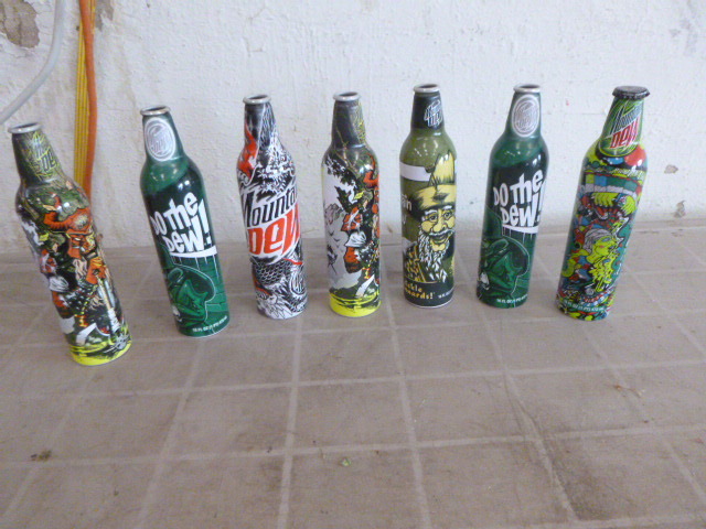 lot 76 image: 7 Collectible Mountain Dew Tin Bottles