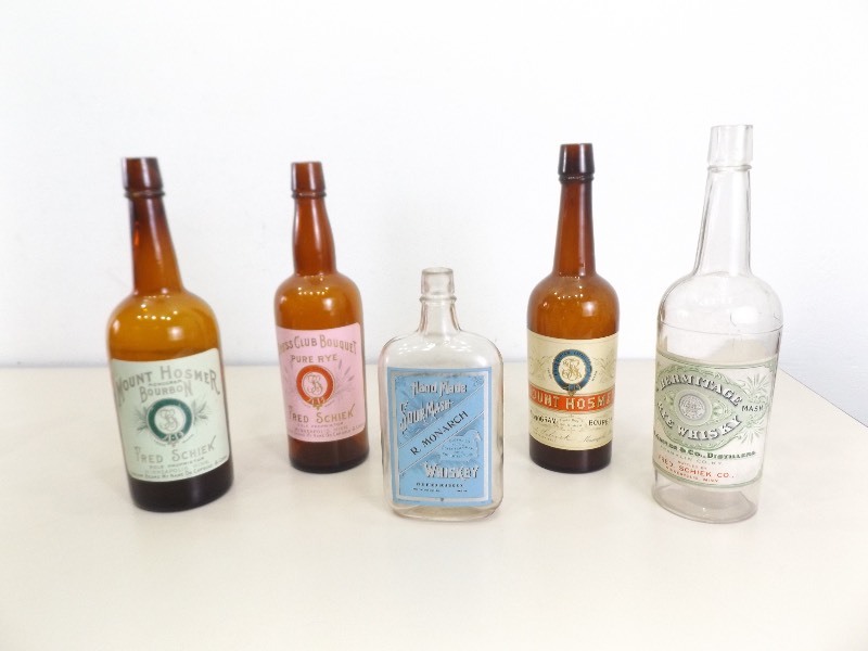 lot 142 image: 5 Antique Fred Schiek Bottlers Whiskey Bottles