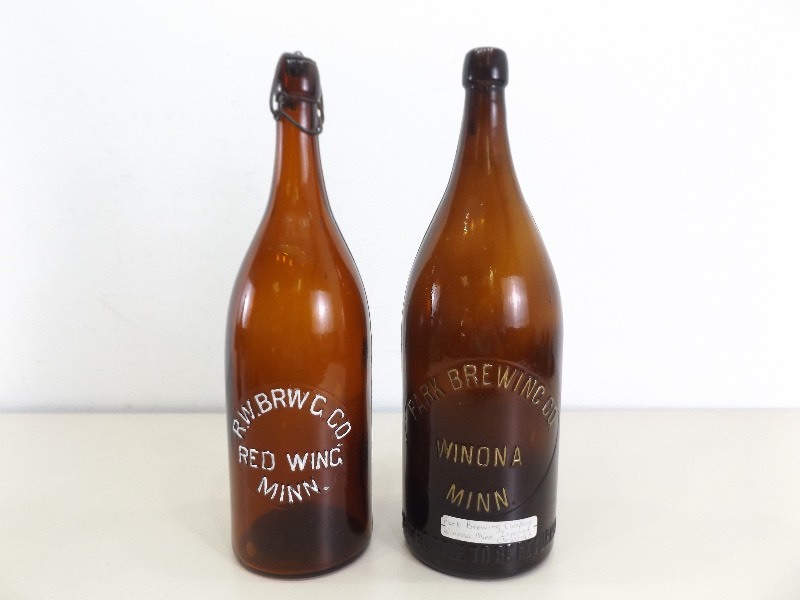 lot 144 image: 2 Antique R.W Brewing Red Wing and Park Brewing Winona Beer Embossed Bottles