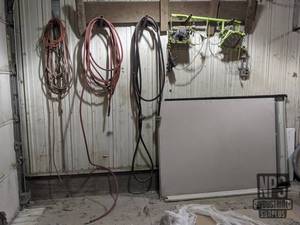lot 142 image: Large Power Cord, Extension Cords, Halogen Worklights and Hoses on Wall