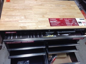 lot 305 image: Husky 46 in. W 9-Drawer, Deep Tool Chest Mobile Workbench in Gloss Black with Hardwood Top whit damage on the side bottom