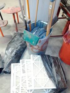 lot 924 image: Can full of shop aprons, misc. shop brooms, plastic sheeting and more.