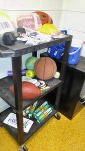 lot 1416 image: Rolling cart with new football, new mouth guards sports balls, and file cabinet.