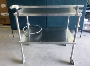 lot 20 image: Phelan Manufacturing Corp. 2 Shelf Heavy Gauge Stainless Steel Cart on Wheels - Please See Taped Break In Back Of Cart - Still A Fantastic High Quality Steel Cart Approx 20x30x40