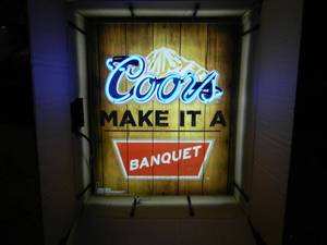lot 16 image: NEW IN BOX ONLY OPENED FOR PICTURES - COORS MAKE IT A BANQUET NEON LIGHT - AWESOME PIECE FOR THE CAVE - APPROX 23 BY 26 - SEE PICTURES