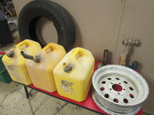 lot 357 image: TRAILER HITCH BALLS, TIRE RIM, TIRE, 5-GALLON DIESEL GAS CANS, JUMPER CABLES, MORE