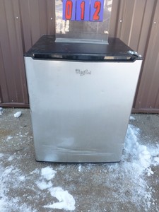 lot 12 image: Whirlpool dorm room refrigerator. Appears lightly used. Has minor dents & scratches. Unable to test in cold warehouse. Needs new cord. As shown.