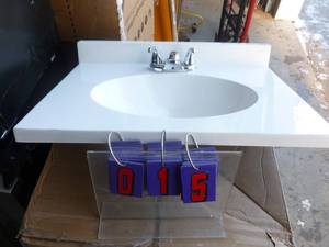 lot 15 image: Vanity top with faucet. 24 x 18. Appears to be a display model. Has a couple of light scratches. Faucet will need hold down nuts. As shown.