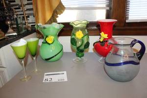 lot 82 image: Lot of (6) Green Crystal Glass Stem Glasses (x2), Green Scalloped Edge Table Vase, Clear Green Glass Yellow Daisy Dcor Scalloped Edge Table Vase, Red Glass Table Vase with Yellow Flower Dcor, Clear Blue Glass Table Pitcher