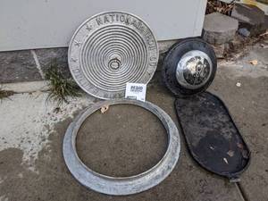 lot 589 image: NIC Manhole Cover in Seat, Ford V8 hubcap, & Cast Iron Skillet