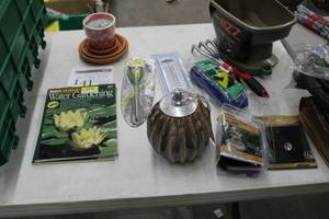 lot 141 image: Lot of (13) Lawn and Garden Supplies - Gardening Books, Scotts Spreader, Pump, Candles, Solar Light, Moisture Meter, Planter Bases, Lawn Furniture Webbing Kit, Corona Garden Claw Tool, Taylor Outdoor Thermometer, Fountain Pump 90 GPH, Solar Step Light
