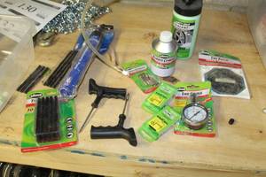 lot 144 image: Lot of Tire Accessories - Gauges, Tire Repair Plugs, Repair Kit, Rubber Cement, Tire Sealant, Hand Pump, Valve Extenders, And More