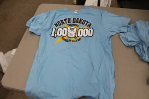 lot 458 image: Lot of (7) Canvas T-Shirt 2X-Large (x1), Medium (x2), Small (x4) Light Blue with North Dakota 1000000 Barrels a Day April 2014 Logo (new)