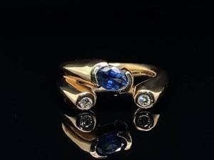 lot 22 image: Modernistic Ring with a Blue Oval Sapphire and Two Diamonds in 14k Yellow Gold $2,999 Retail