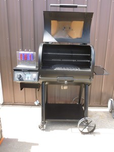lot 1 image: Oklahoma Joe pellet grill. Cast iron grates. Lightly used. Powers up. Appears to function. Something seems jammed in auger As shown.