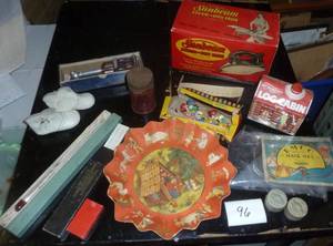 misc collection of vintage items, cardboard serving plate, hair nets, toothpick angels for cake decorating I assume, old sunbeam iron box, slide rule, baby shoes, and a mustimeter