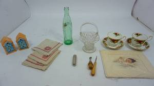 lot 75 image: Cups & Saucers--Crystal Brides Basket--Birdhouse Salt & Pepper Shakers--Empty Coca Cola Bottle--Tracing Wheel & Rug HookMatted Baby Picture--Two Cloth Napkins