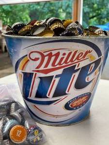 lot 322 image: Miller Light Tin Full of Bottle Caps and a Bag w More