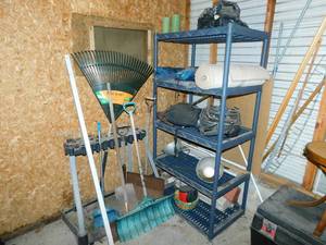 lot 45 image: Leaf Rake-Vintage Handled Dust Pan-Vintage Snow Shovels--Five Shelf Blue Storage Shelf With Two Folding Canvas Camping Chairs In Removable Carrying Bags--Electric Fan---Garage Hanging Electric Light--Two Easter Baskets-Garage Tool Rack