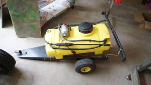 Yellow 15 Gallon Liquid Fertilizer Spreader That Is Towed Behind Riding Lawn Mower