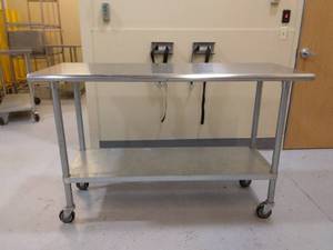 lot 84 image: MSRP $700 Advance Tabco ELAG-245 60 16 gauge Medical NSF Grade Mobile&nbspSurgical Instrument &nbspWork Table w Galvanized Steel Undershelf & 430 Series Stainless Flat Top On Wheels - Great Condition