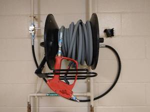 lot 114 image: Hotsy Pressure Washer Red Trigger Gun (Can handle 5000psi), Hose & Wall Mount Rack Only - Great Condition - No Pressure Washer Mechanism (Had been wired into building) 