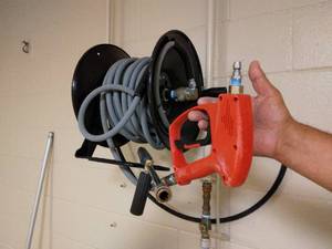lot 115 image: Hotsy Pressure Washer Red Trigger Gun (Can handle 5000psi), Wand, Hose & Wall Mount Rack Only - Great Condition - No Pressure Washer Mechanism (Had been wired into building) 