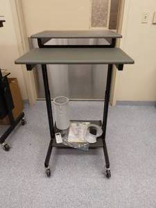 lot 7A image: MSRP $160 Uline&nbspMulti-Level Tilting Height Adjustable Sit Stand Computer Work-Station Podium Mobile Cart With Lower Printer Shelf - Grey & Black - Excellent Condition - ElectronicsContents Not Included