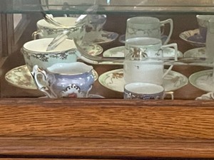lot 231 image: Antique Tea Cups and Saucers on the Bottom Shelf of the Curio Cabinet