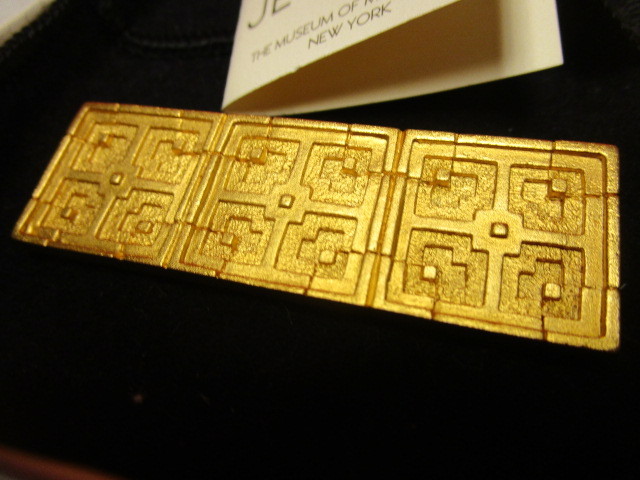 lot 331 image: FRANK LLOYD WRIGHT JOHN STORER HOUSE 22 KT. GOLD-PLATED JEWELRY PIN, ISSUED BY MOMA