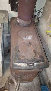 lot 212 image: Cast Wood Stove with Chimney Parts and Cement Block.