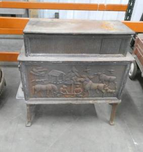 lot 108 image: A very decorative cast iron furnace  stove.  Front and Back Sides feature great relief work with Moose, a cabin and guys cutting down a tree.  This would be a great piece for a cabin.