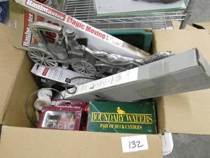 lot 132 image: Large box of misc household dcor, mini blinds, new candles, xmas, bathroom bar, wall hangings, vintage hair dryer, new rug for around the toilet and toilet cover, table placemats, kitchen timer, travel clock, wicker basket, old radio (works)