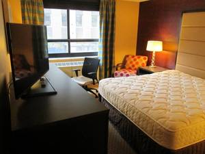 lot 167 image: Room 919. King bed, Polka Dot Chair, Small Safe, Mini Fridge, and more
