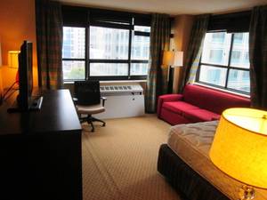 lot 168 image: Room 920. King Bed. Classy Red Couch, Mini Fridge, and Decor