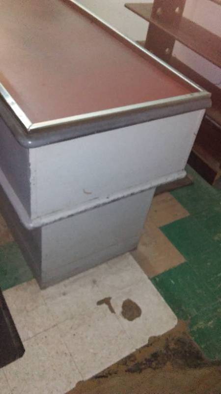 lot 19 image: Retro Style Wood Checkout Stand. 122 in. x 25.5 x 33 in. H. Cash Register Stand is attached.